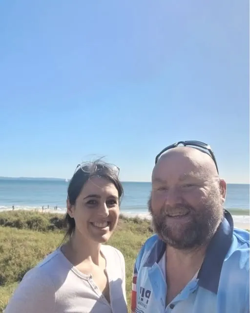 A participant and his support worker at the beach